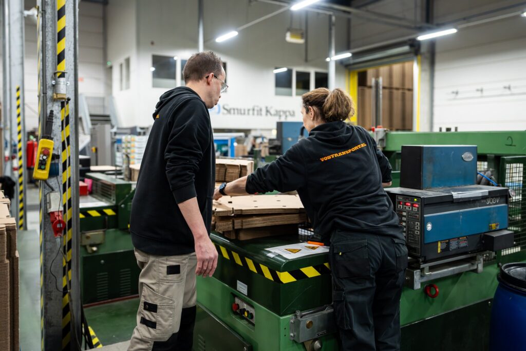 Twee medewerkers bij de verpakkingsmachine in de Vos Transport assemblagehal