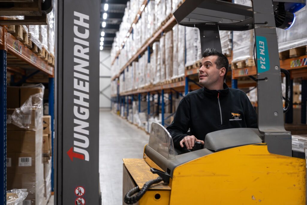 Medewerker bestuurt heftruck in magazijnpad bij Vos Transport